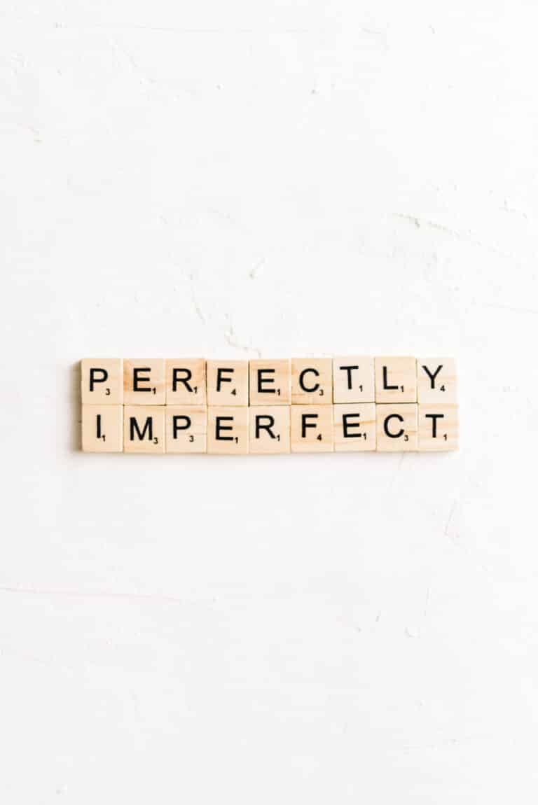 Scrabble tiles laying on a white background spelling out "perfectly imperfect".
