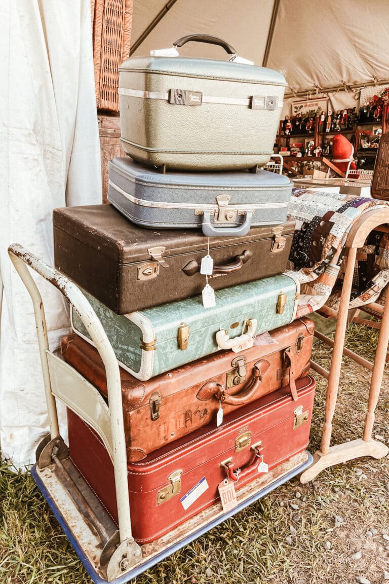 A stack of antique suitcases stacked up on a rolling cart.