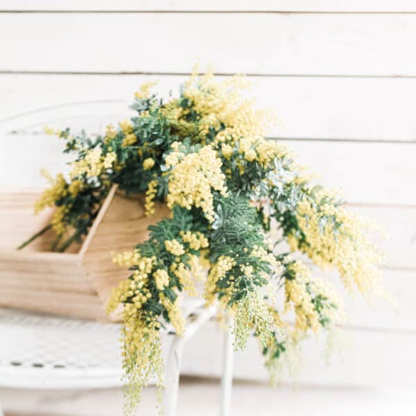 Yellow flowers in a wooden basket on the table.