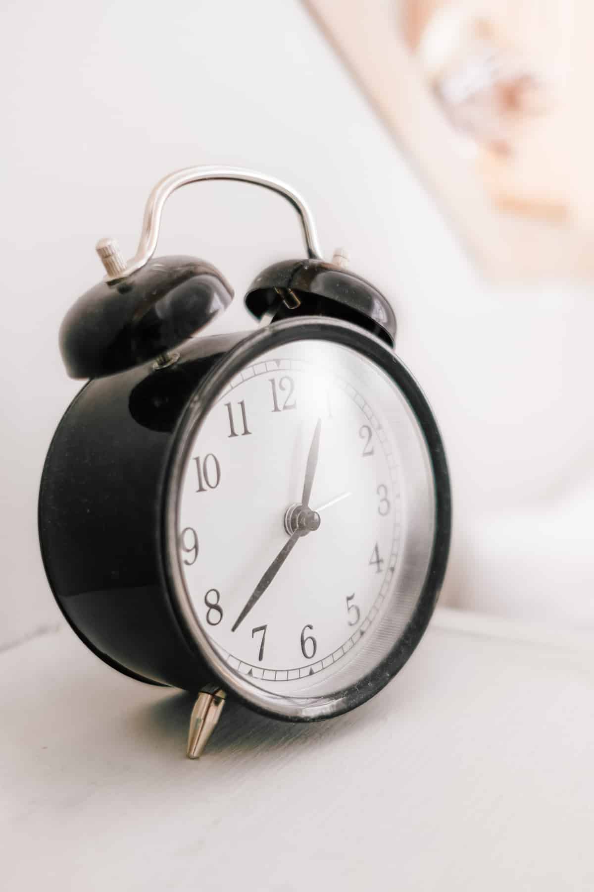 A black alarm clock sitting on a nightstand.