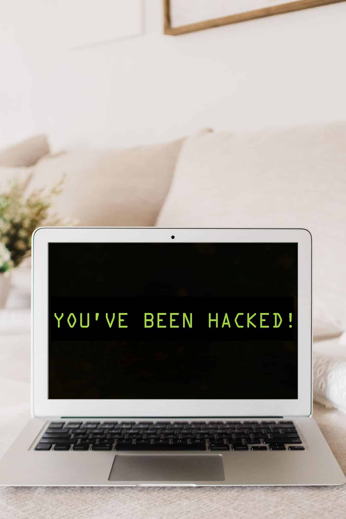 An open laptop sitting on a couch with the words "you've been hacked" on the screen.